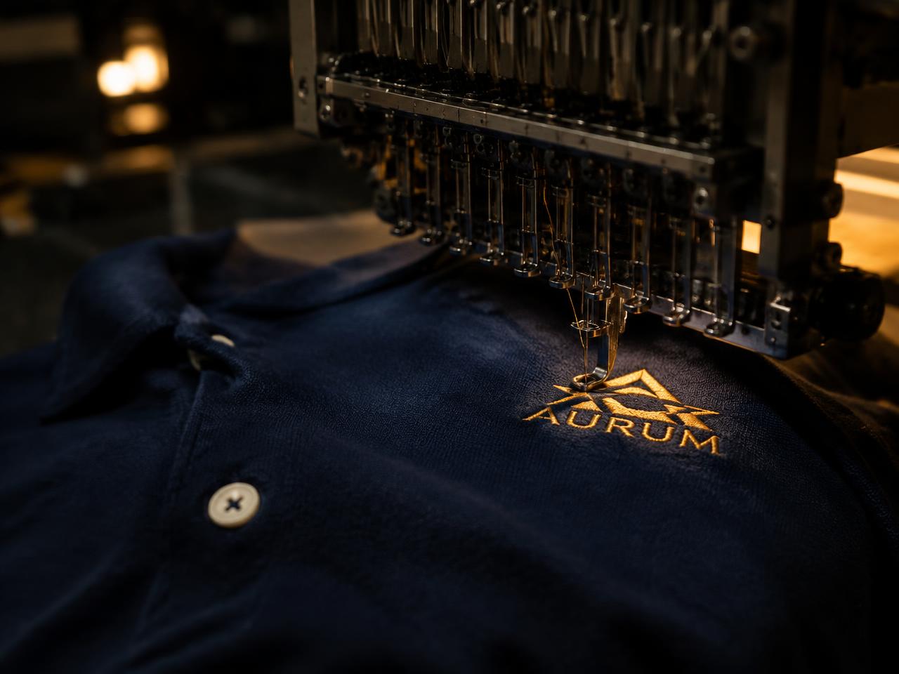 Embroidery machine stitching a gold logo onto a navy polo